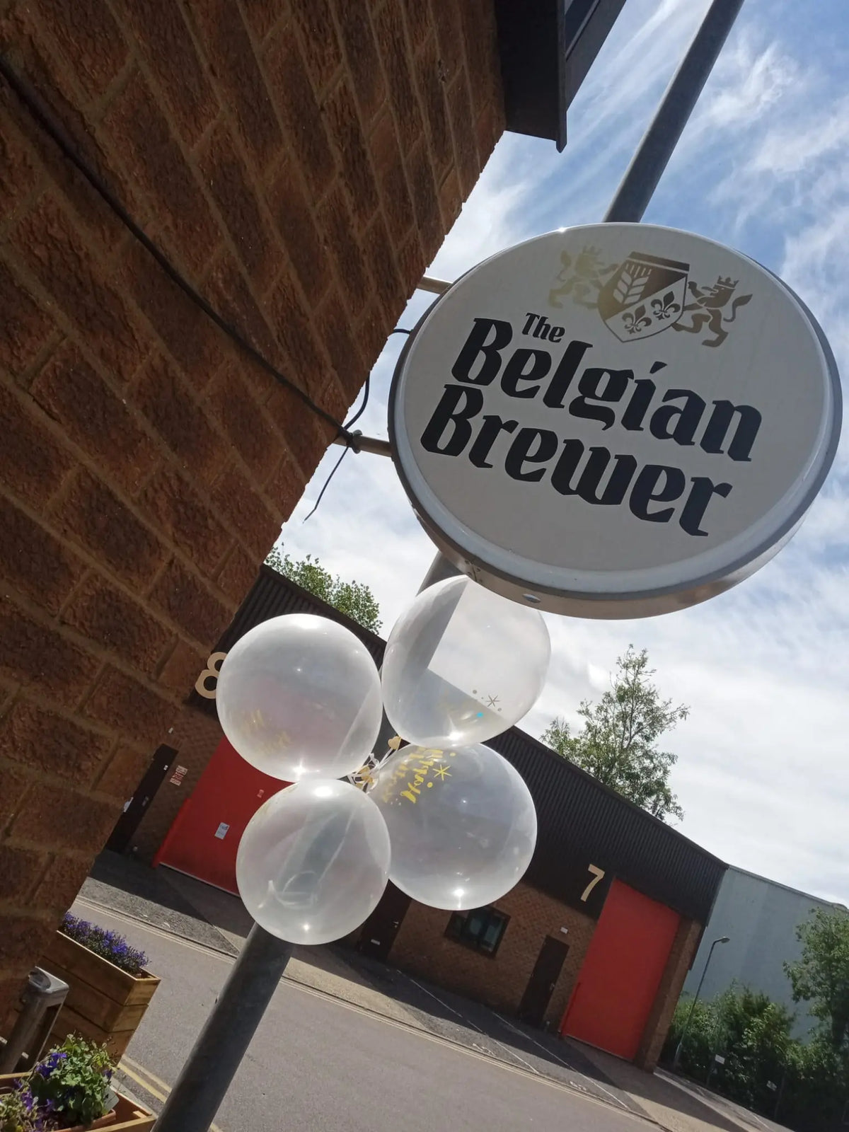 The Belgian Brewer hanging sign outside the Stortford taproom at The Links Business Centre, with balloons tied to the post