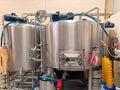The brewhouse at The Belgian Brewer in Bishop's Stortford: stainless steel mash tun and kettle, with kegs stacked beside them